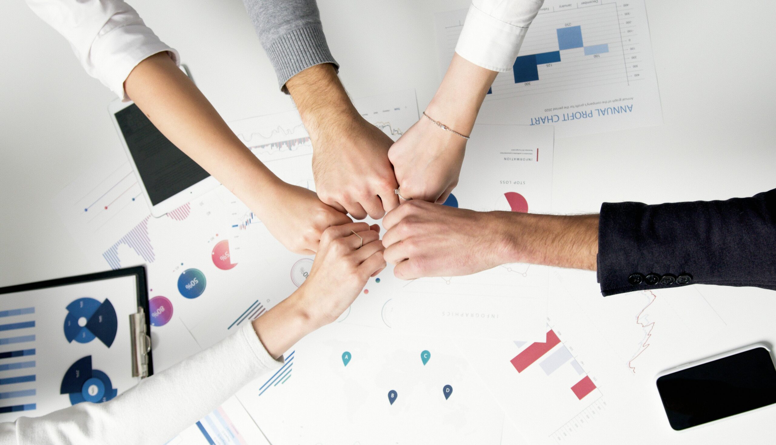 How-Smart-IT-Boosts-Employee-Morale-and-Keeps-Your-Best-People-scaled.jpg Free Colleagues celebrate success with a fist bump over financial charts depicting teamwork and unity. Stock Photo